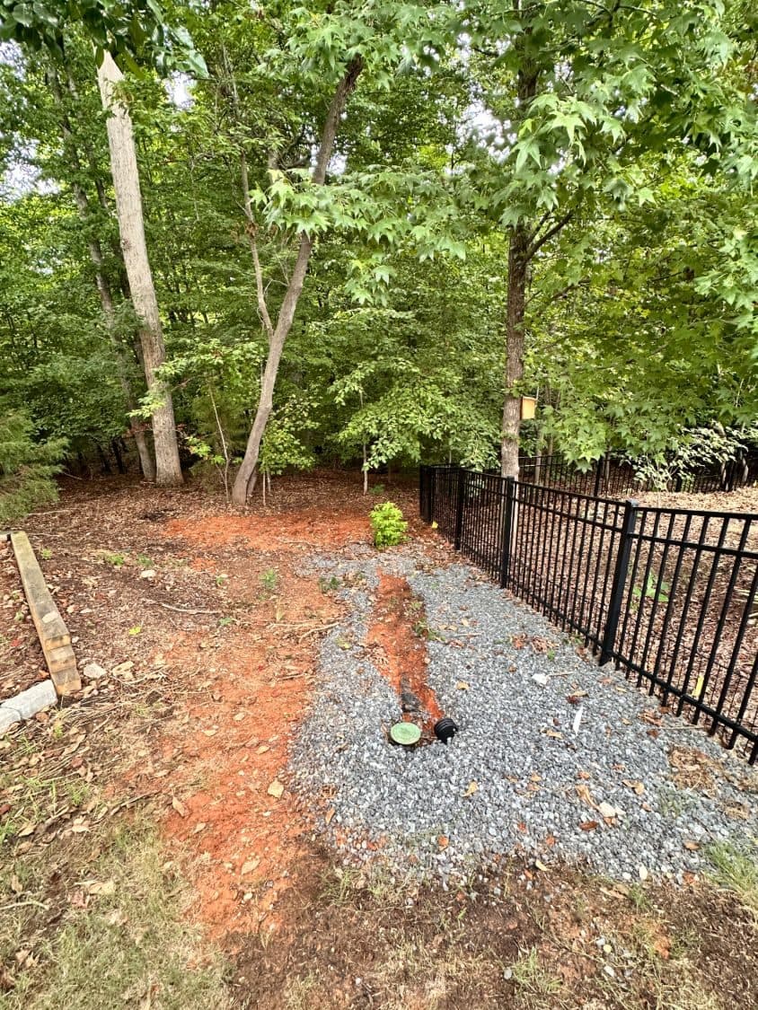 Buried drain line and cleanouts running through a gravel bed before the stone was placed