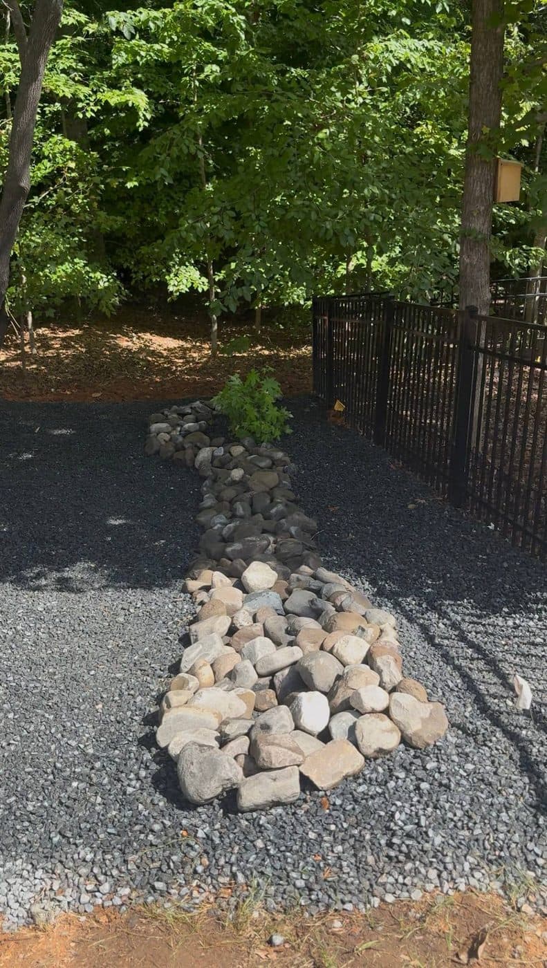 The finished dry creek bed of river rock carrying water along the same run